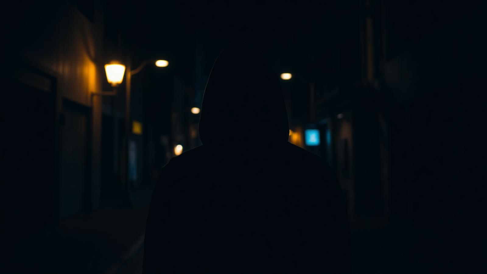 Silhouette d'un jeune dans une rue sombre
